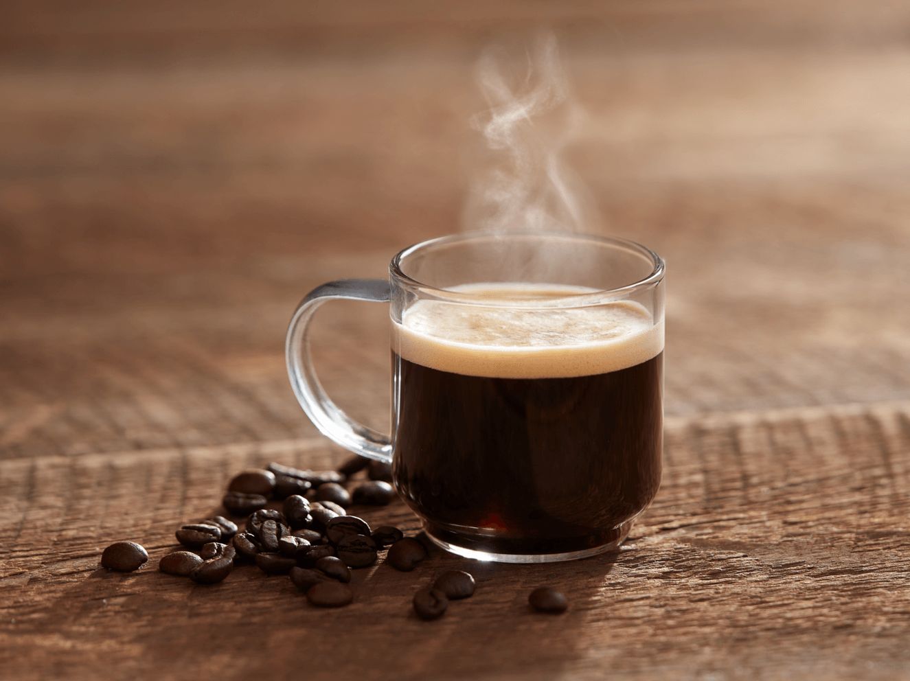 Taza de café humeante con granos de alta calidad, ideal para negocios que buscan un proveedor de café al por mayor.