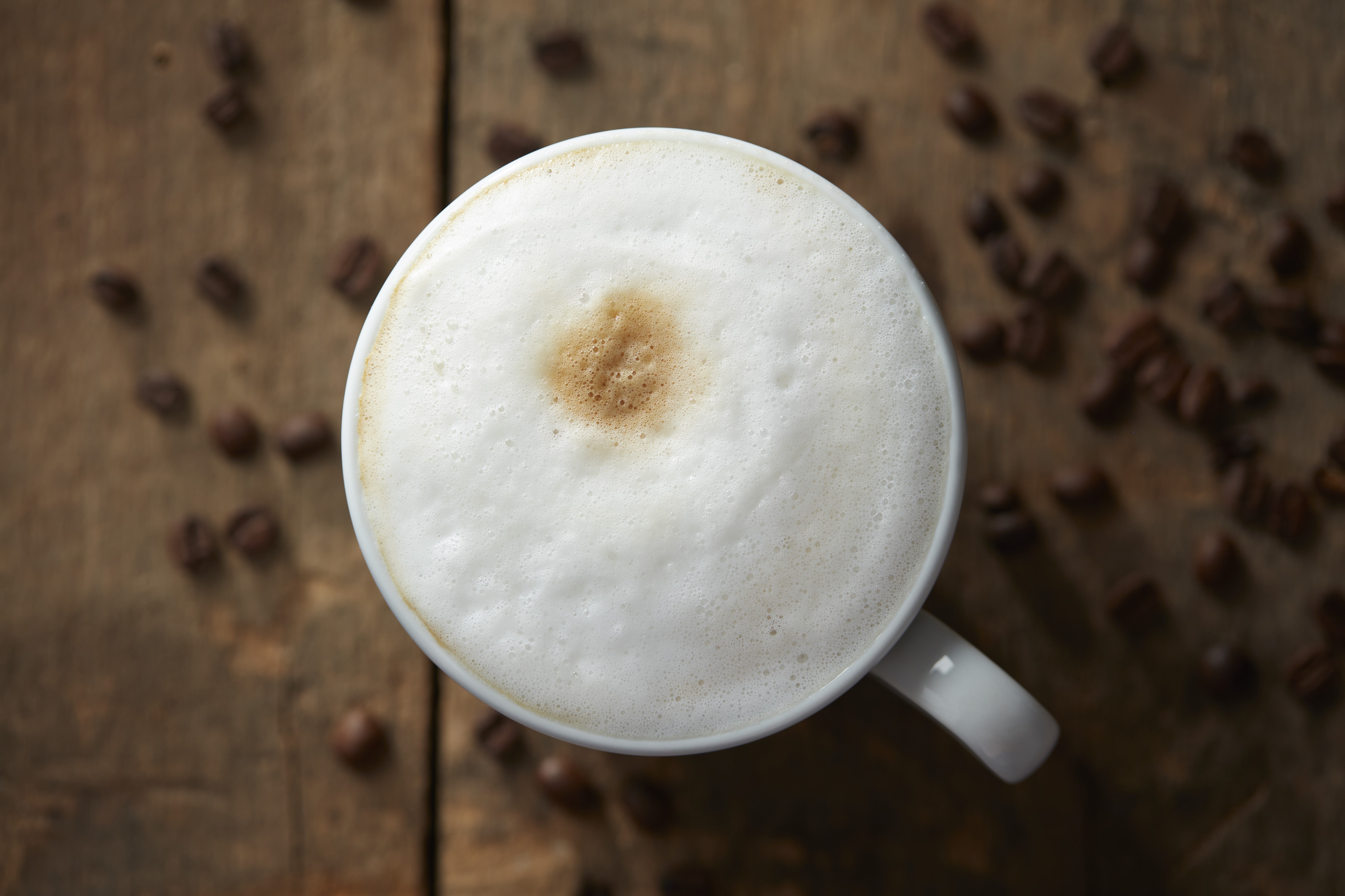 Taza de café humeante con granos de alta calidad, ideal para negocios que buscan un proveedor de café confiable