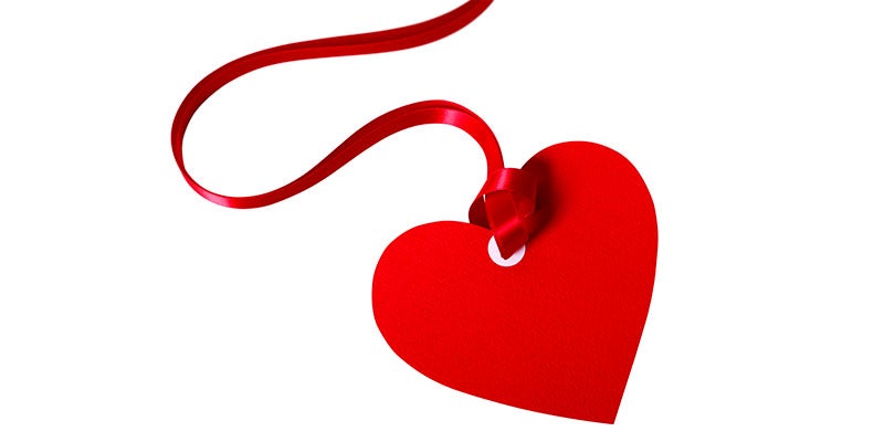 Corazón hecho en papel y con listón para decorar una cena romántica