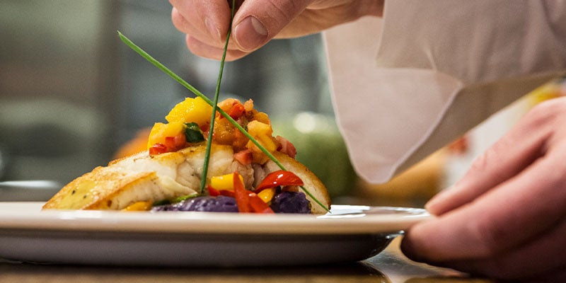 Chef decorando el plato fuerte de una cena romántica