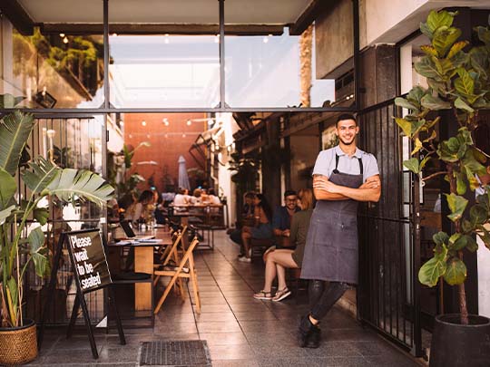 Dueño de restaurante posando en la entrada de su negocio