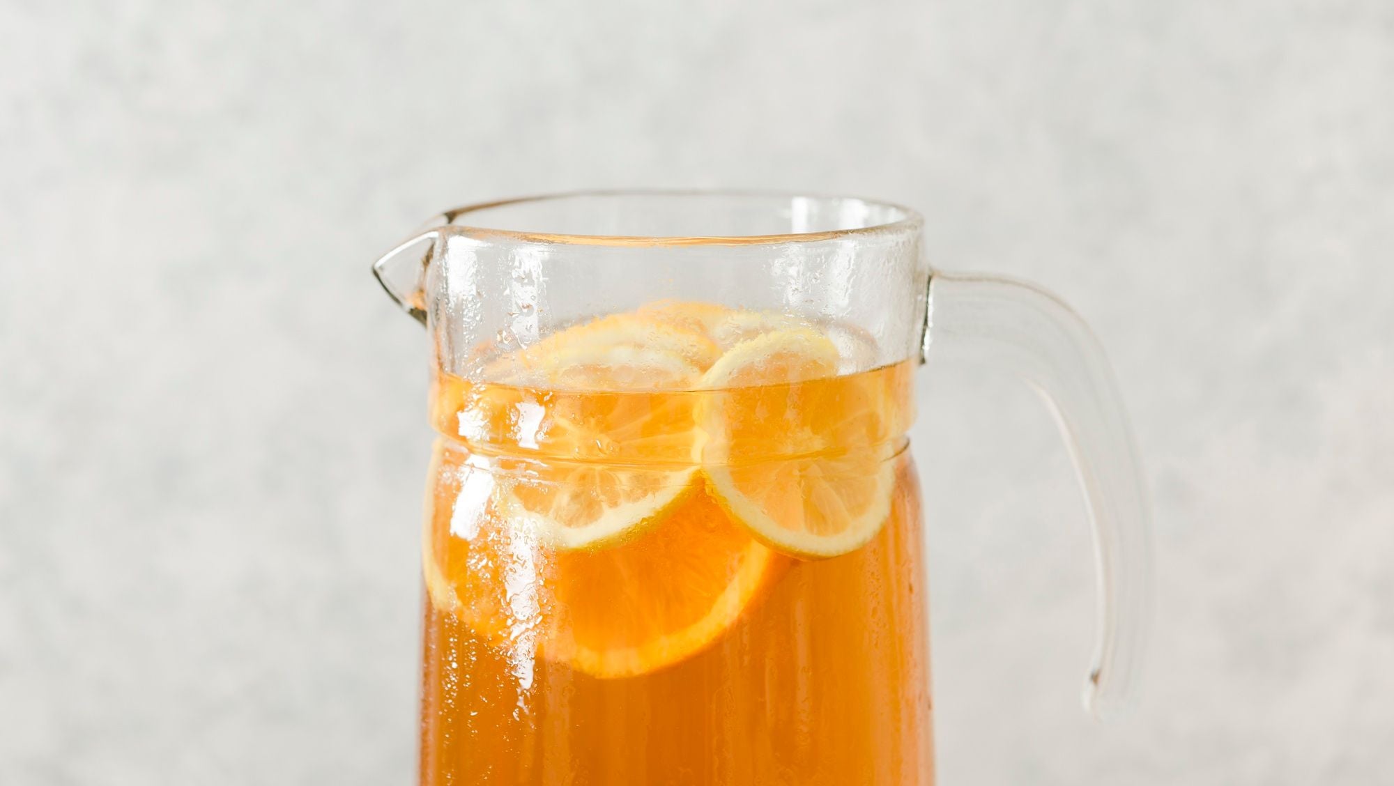 Una jarra de vidrio con bebida NESTEA® acompañada de limón.