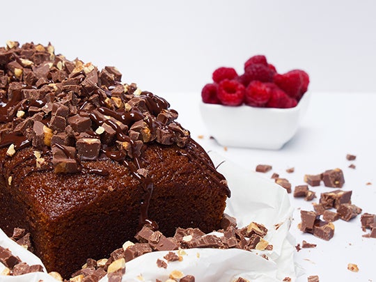 Bizcocho elaborado con chocolates al por mayor, con un bol de frambuesas de fondo.