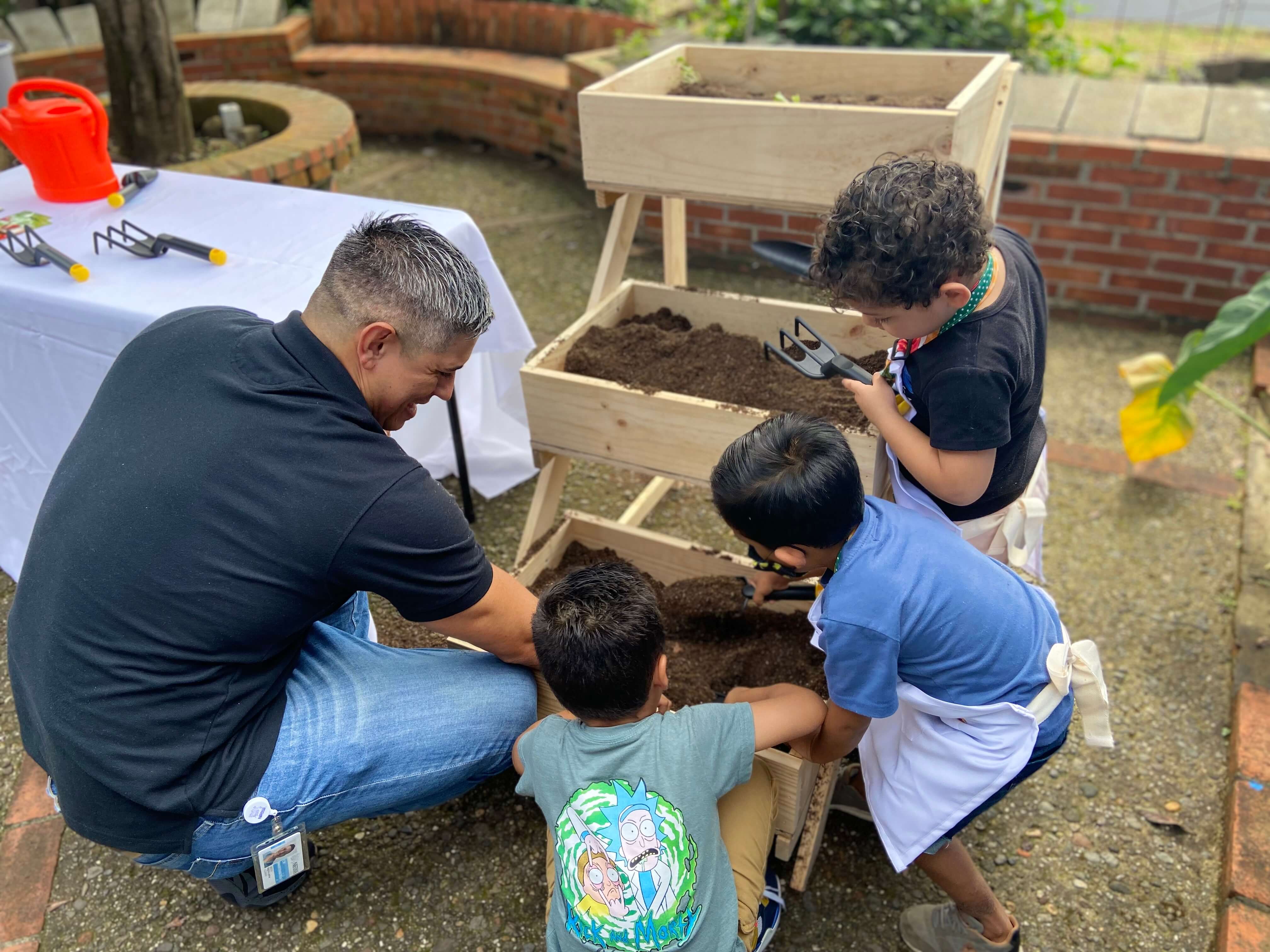 Instructor con niños sembrando vegetales y frutas en una huerta