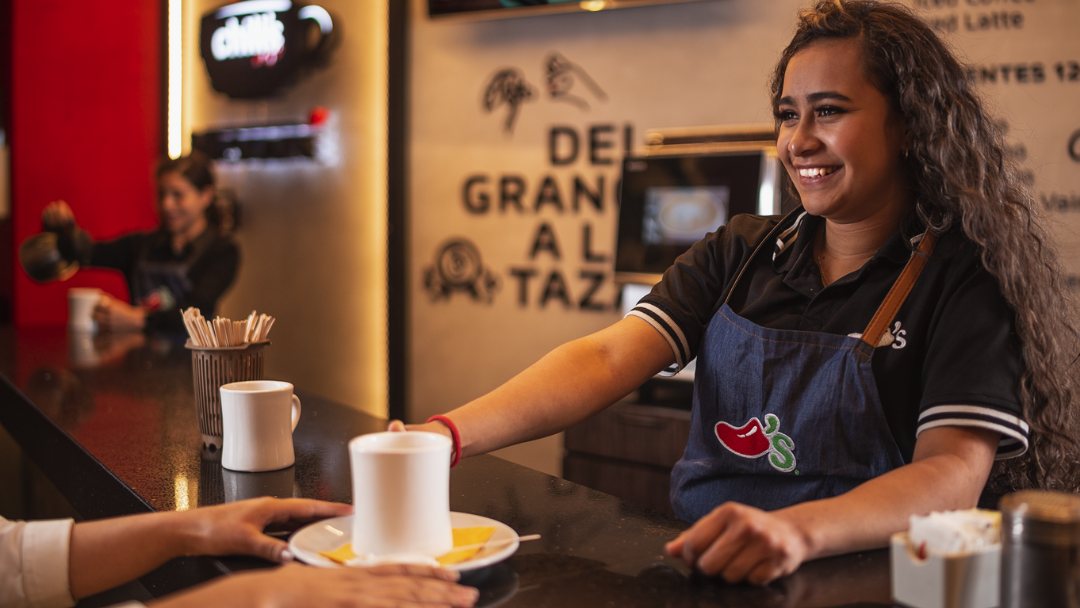 Una trabajadora de Chili's sonriente, ofreciendo la experiencia con NESCAFÉ®