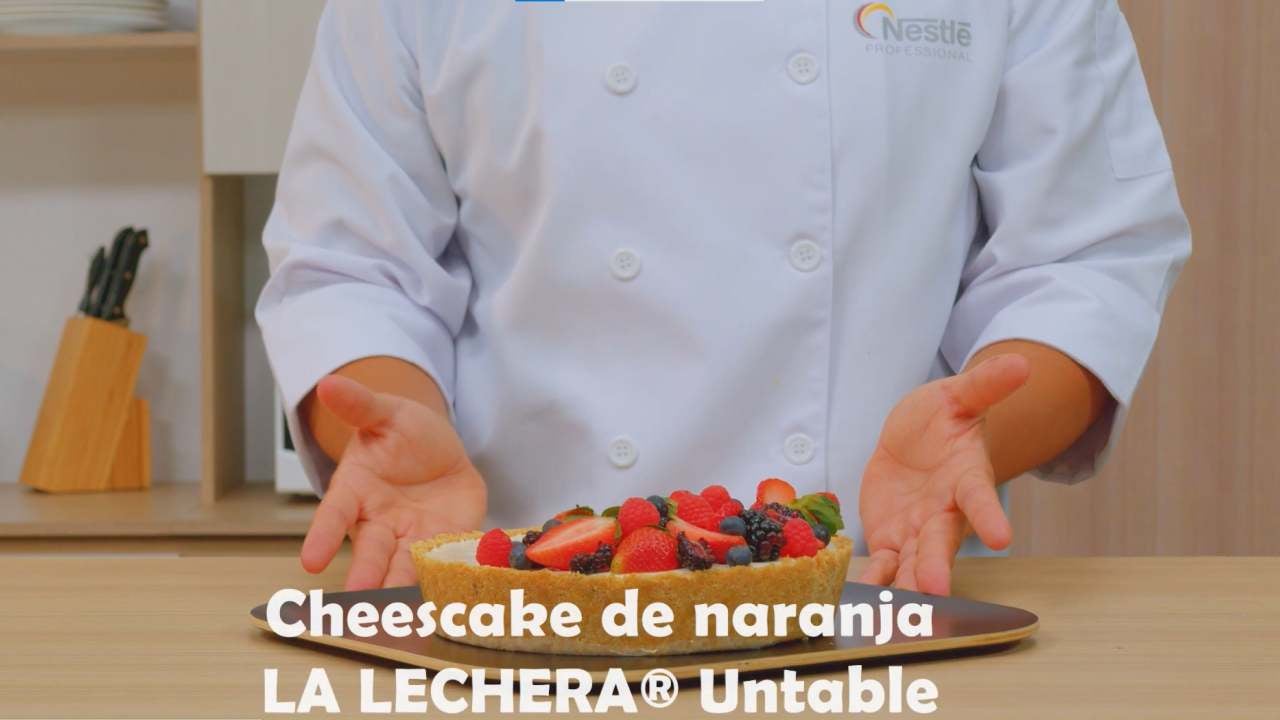 El torzo de un chef presentando un cheescake de naranja realizado con LA LECHERA® untable