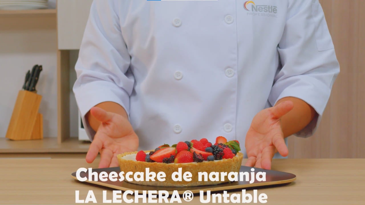 Torzo de un chef presentando un cheescake de naranja hecho con LA LECHERA®
