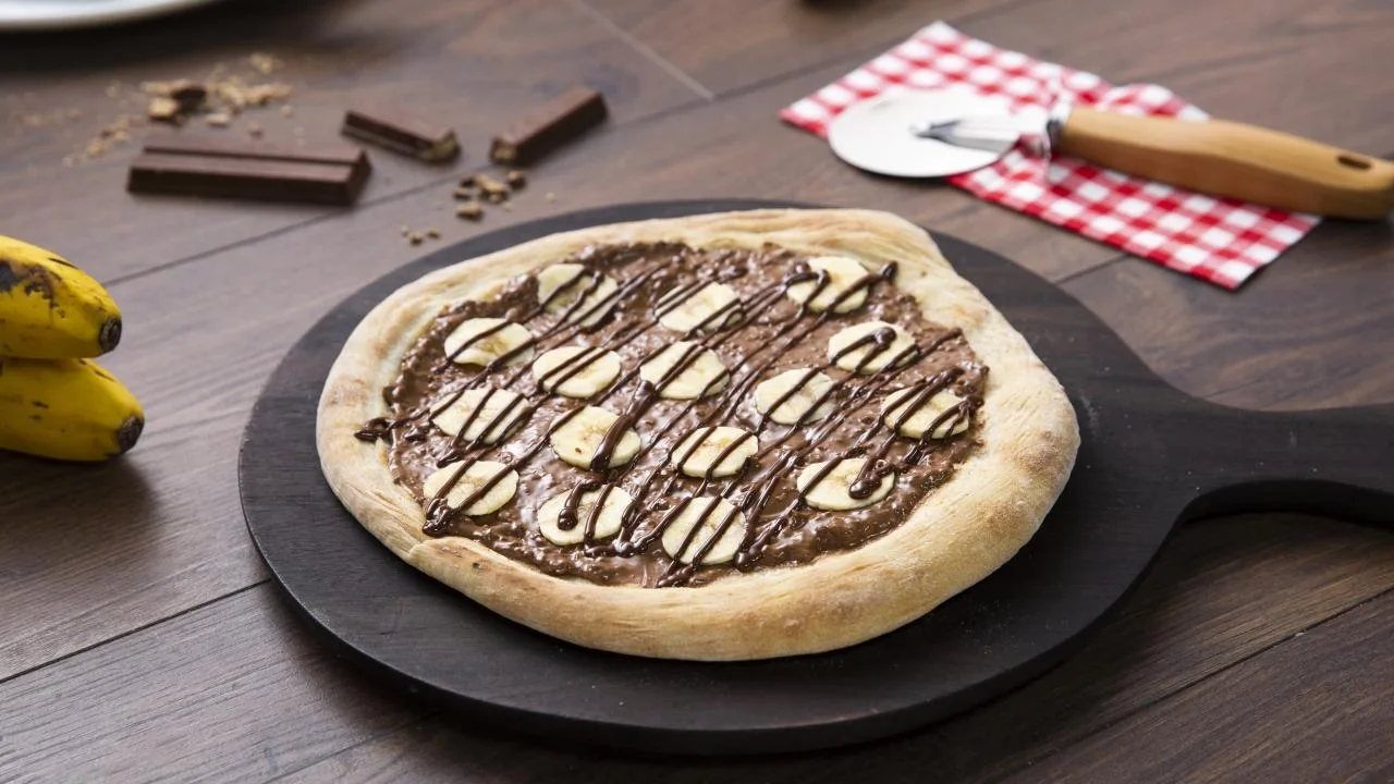 Una pizza dulce con KITKAT® untable, trozos de banano y chocolate derretido