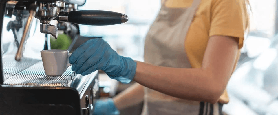 Barista manipulando bebida de café con guantes azules