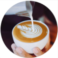 Mano de barista decorando una taza de café con espuma de leche