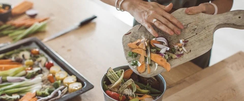 Manos de mujer almacenando desperdicios de alimentos en un recipiente
