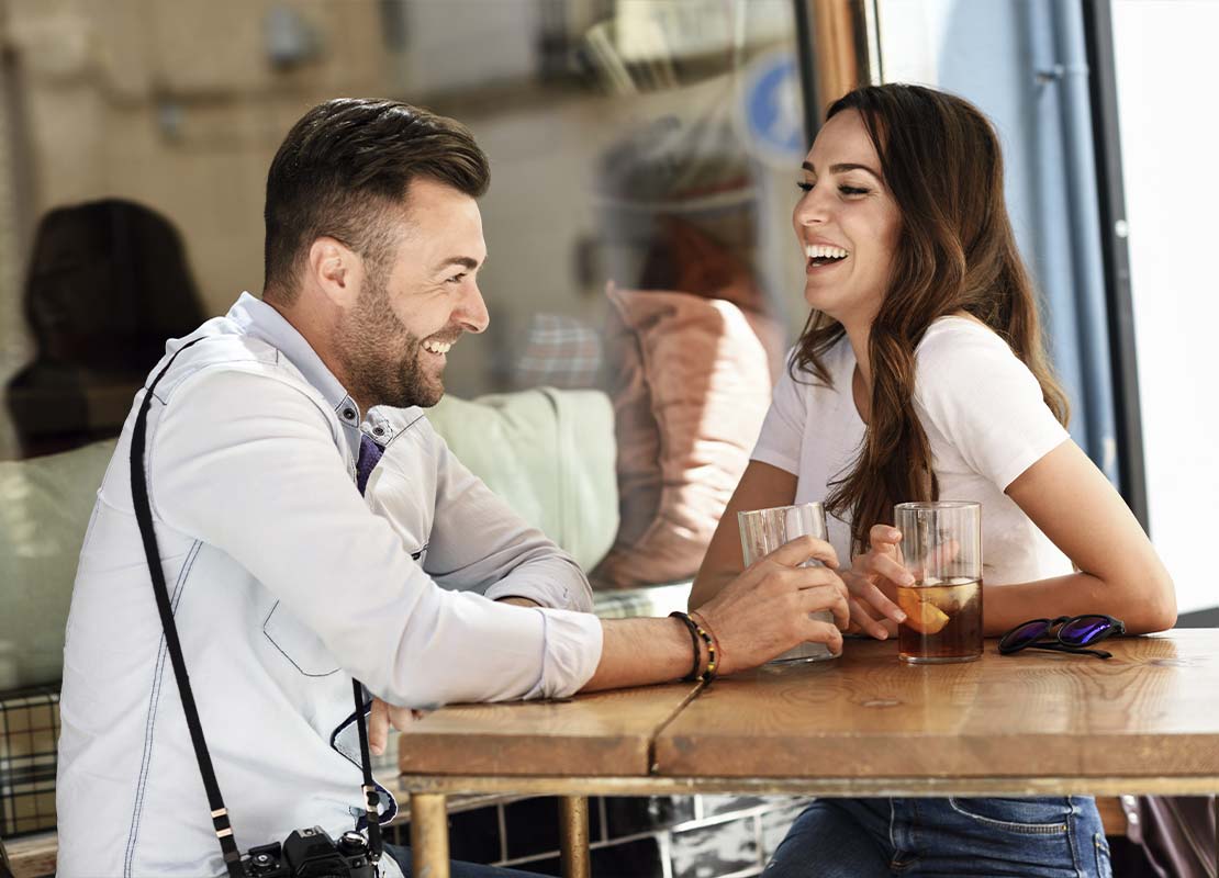 Pareja de Millennials disfruta de una bebida fría en la terraza de una cafetería