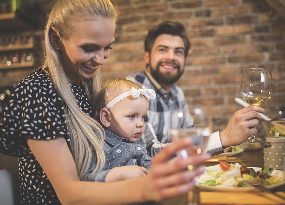 Pareja joven Millennial y su bebé disfrutan de una cena en un restaurante moderno