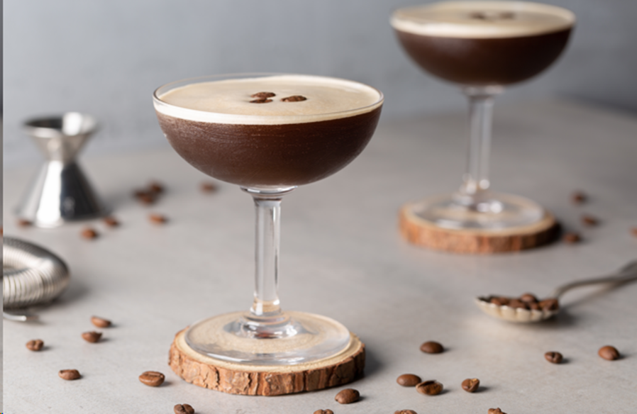 Cócteles sin alcohol como dos Martini Espresso sobre un portavasos de madera, decorados con granos de café