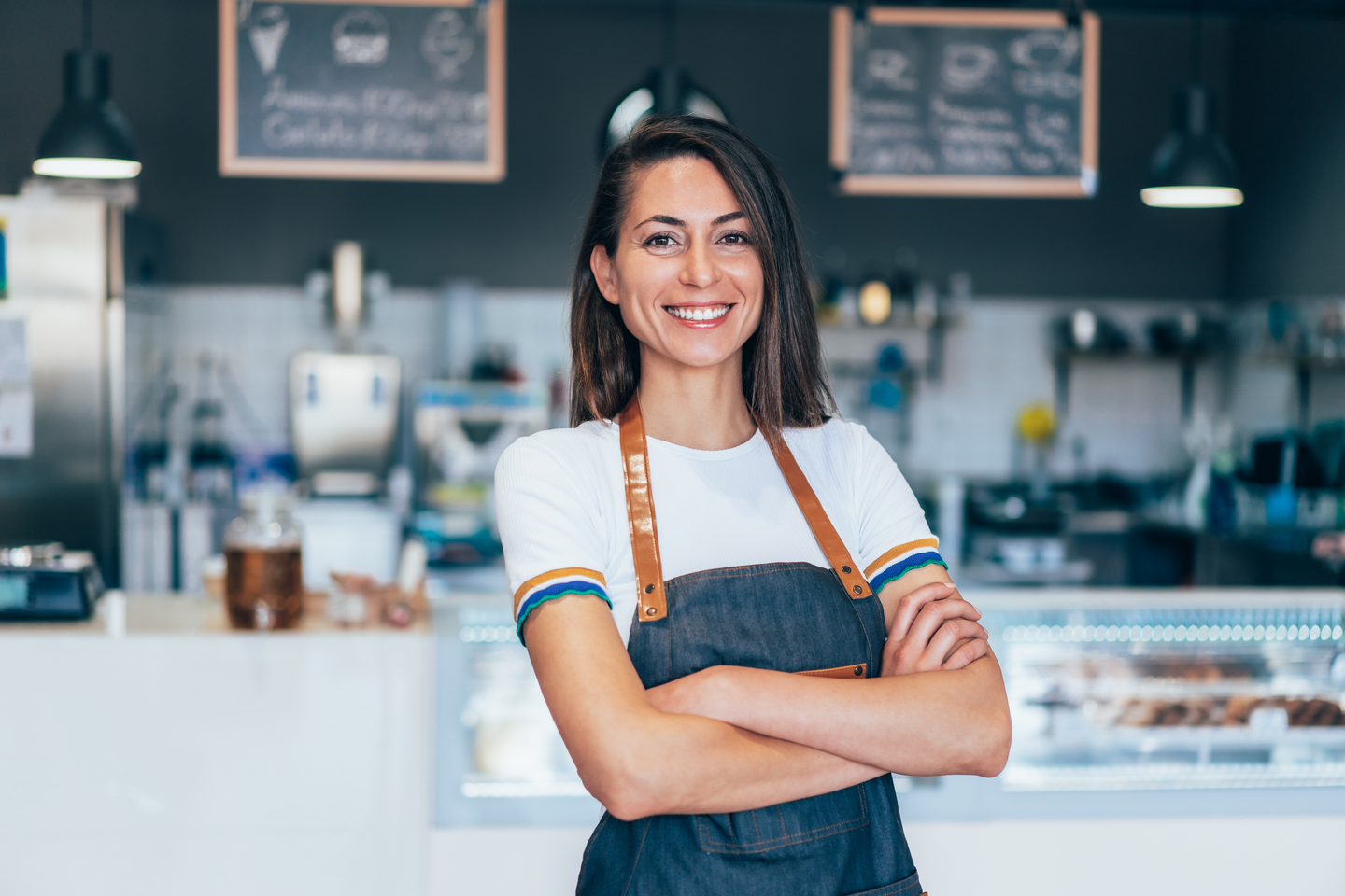 Mujer barista con los brazos cruzados y sonrisa