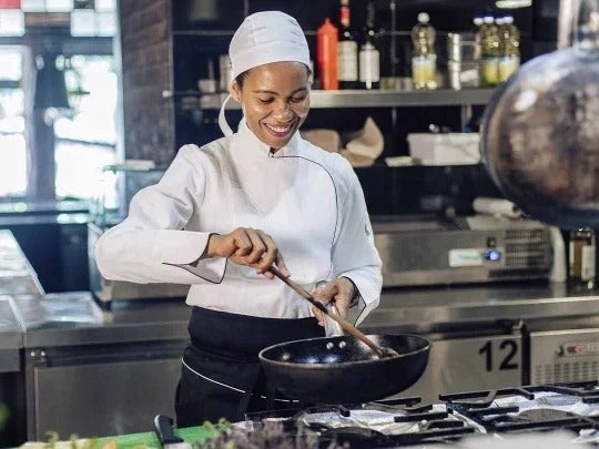 Chef cocinando en su cocina con una amplia sonrisa