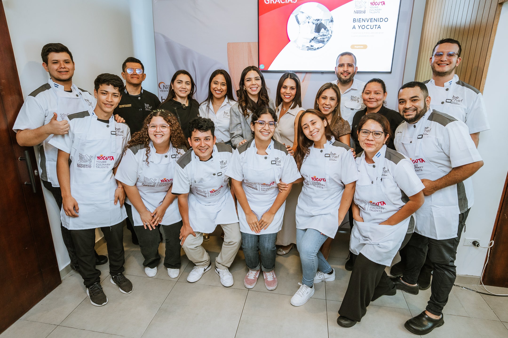 Grupo de jóvenes con mandiles blancos sonríen para la cámara, celebrando el lanzamiento del programa YOCUTA 2.0 de NESTLÉ®