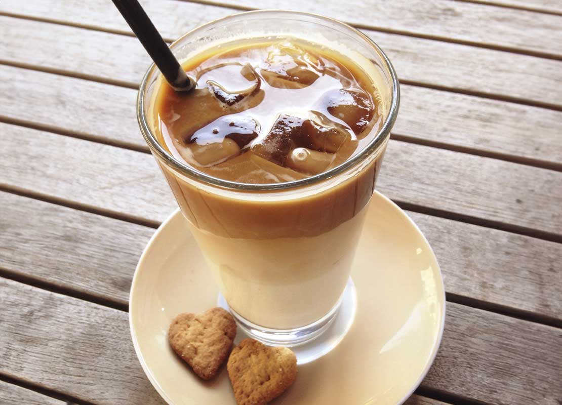 Vaso de café bombón con galletas en forma de corazón en un plato, un ejemplo de café de sabores