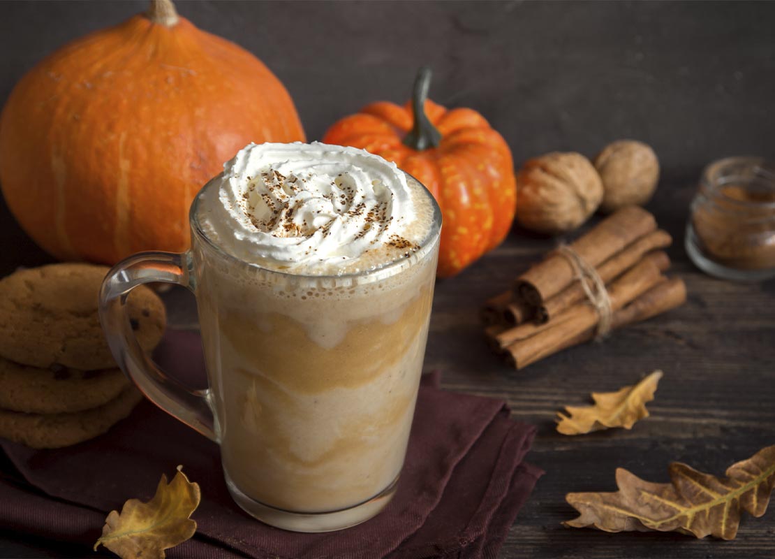 Latte de especias de otoño rodeado de decoración otoñal como especias de temporada, galletas y calabazas