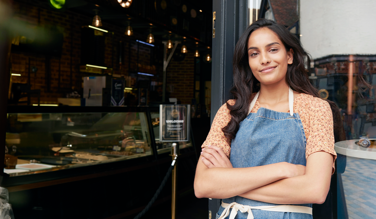 Dueña de un negocio de food service sonriendo frente a su local lista para ofrecer menús nocturnos