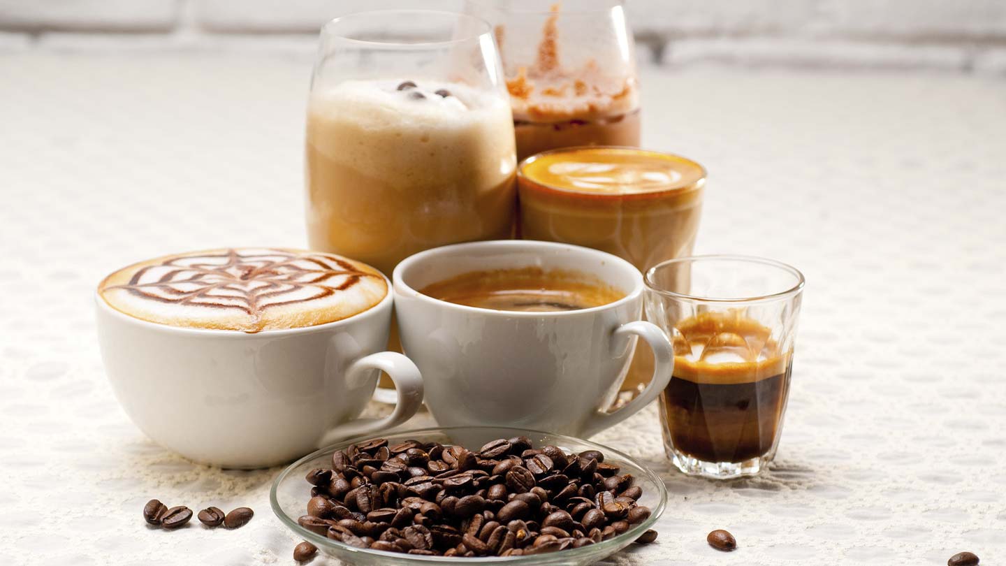 Granos de café tostados y 6 bebidas en diversos tipos de tazas como espresso, café frío, americano, entre otros