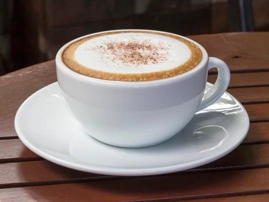 Una taza de capuchino con espuma hecho con productos de un proveedor de café y crema para café al por mayor.