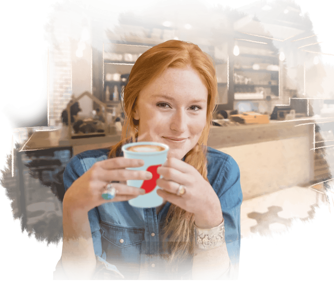 Mujer sostiene un vaso de NESCAFÉ® en una cafetería