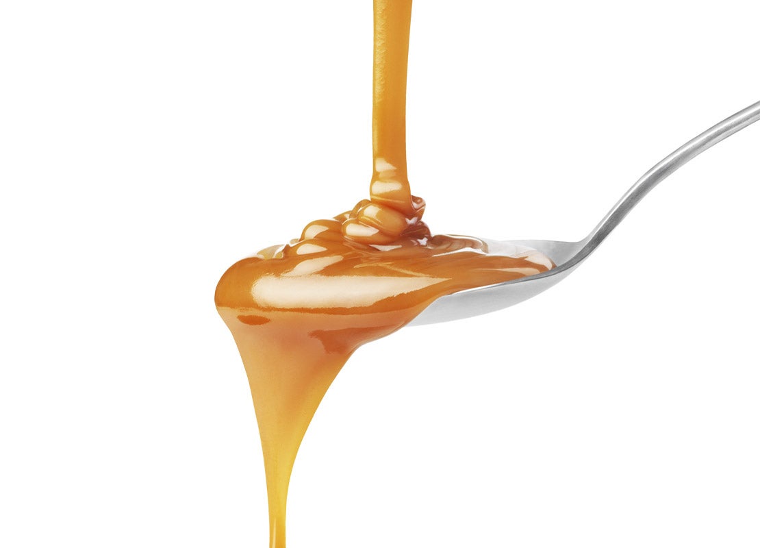 Productos lácteos como NESTLÉ® El Manjar vertida sobre una cuchara