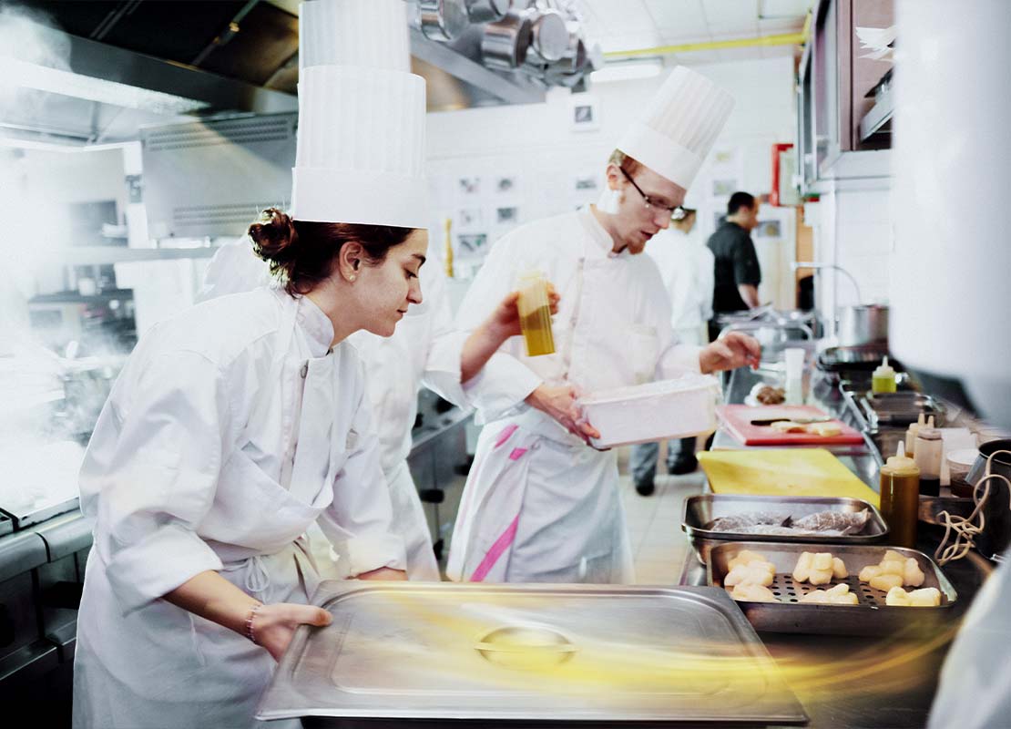3 Jóvenes estudiantes del Programa YOCUTA realizan preparaciones en una cocina comercial