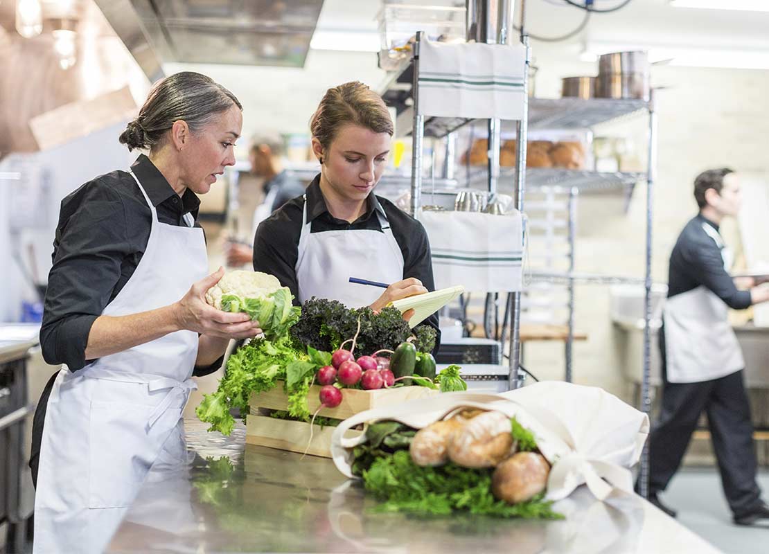 Chefs revisan en una cocina comercial el inventario de las verduras que llegan a su restaurante