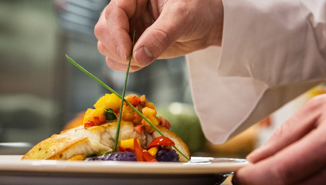 Cocinero emplatando su platillo delicadamente en un servicio de catering.