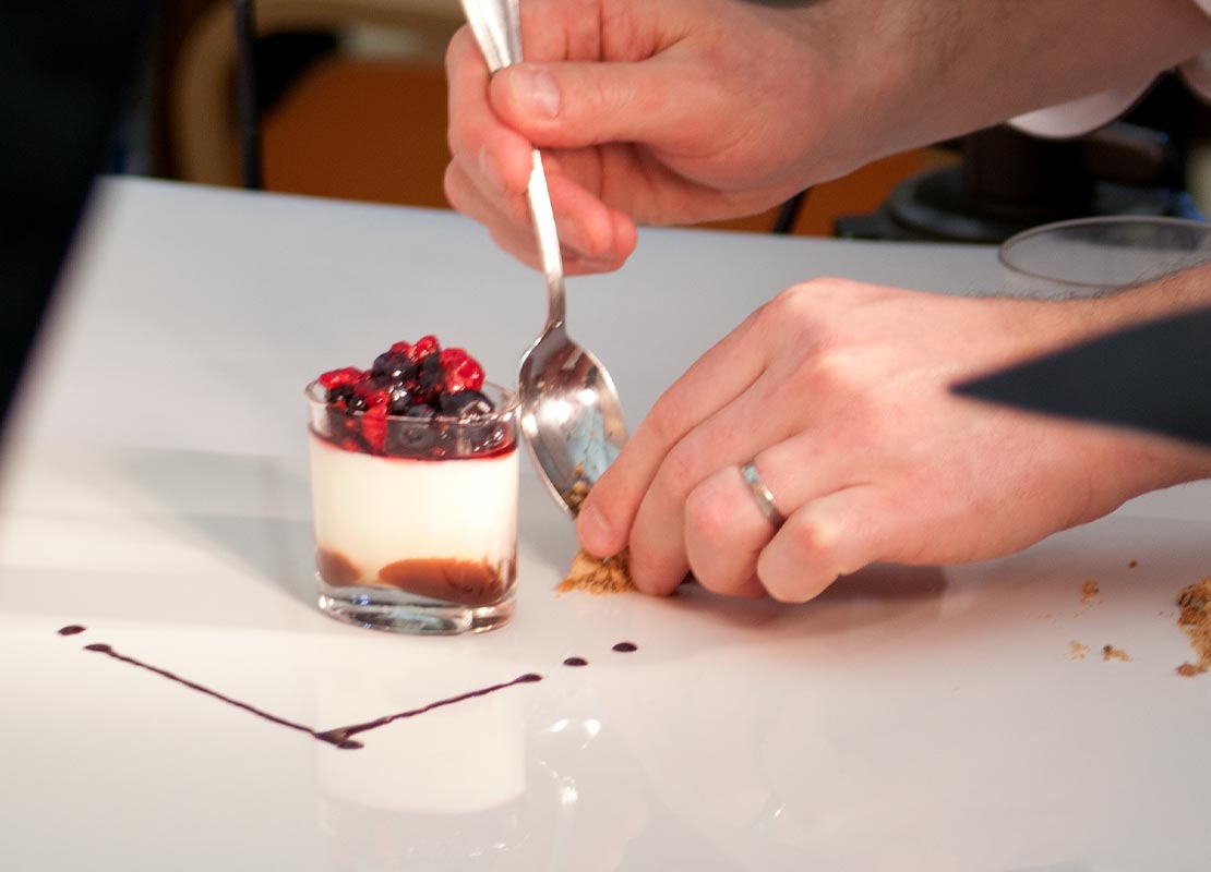 Manos de repostero decoran el plato para servir un postre de frutas silvestres en un vaso