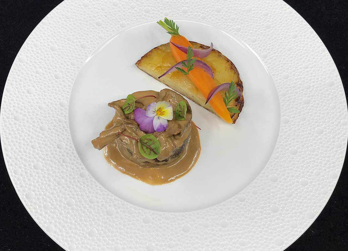 Paletilla de ternera en guiso, emplatado con microvegetales y flores comestibles