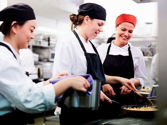 Tres jóvenes chefs uniformados cocinando.