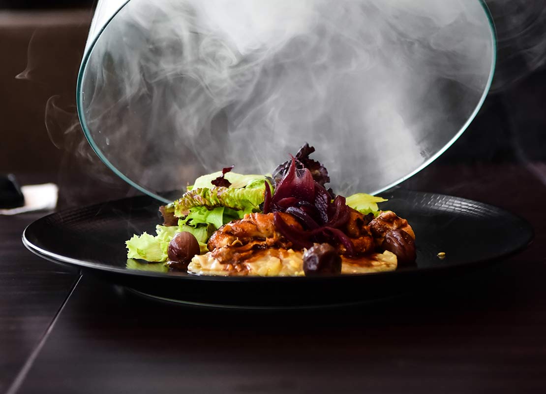 Retiro de cubreplatos de cristal de un plato negro humeante con comida
