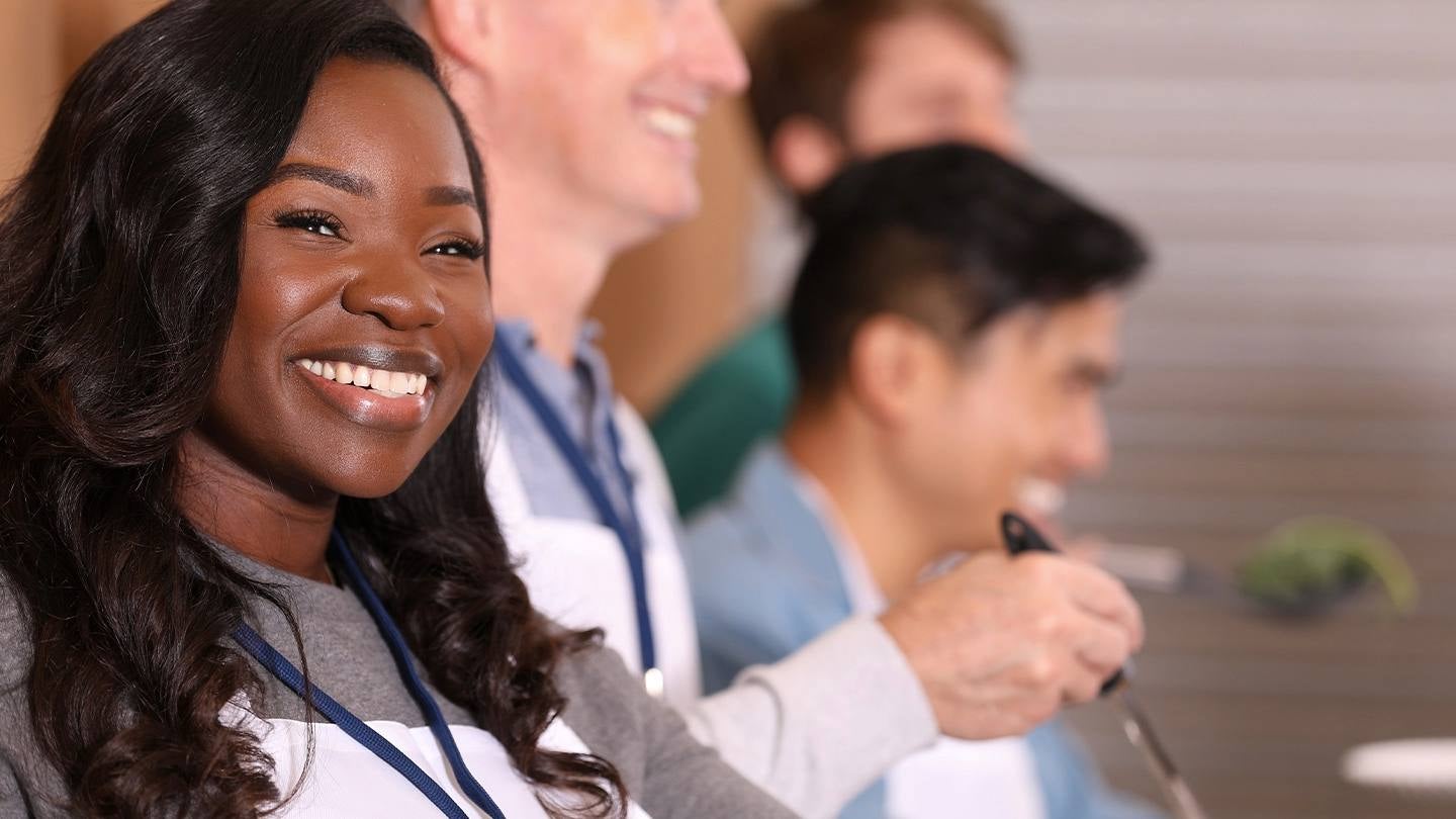 Colaboradores sonrientes del sector HORECA con delantales y gafetes sirven comida