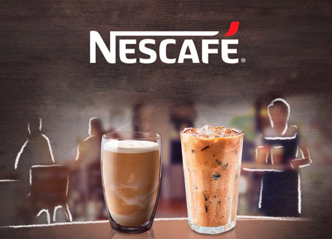 Dos bebidas NESCAFÉ® frías frente a un fondo difuminado con siluetas de personas en una cafetería