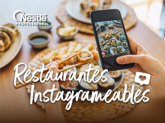 Una mano sostiene un teléfono que fotografía un plato de sushi