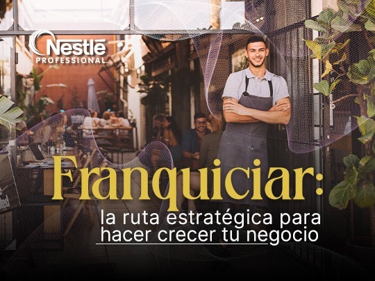 Emprendedor con delantal en la entrada de su negocio, representando el concepto de franquiciar.