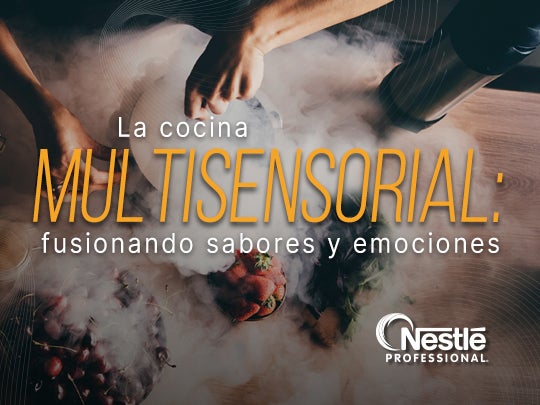 Mesa con recipientes e ingredientes mientras unas manos preparan alimentos envueltos en humo decorativo