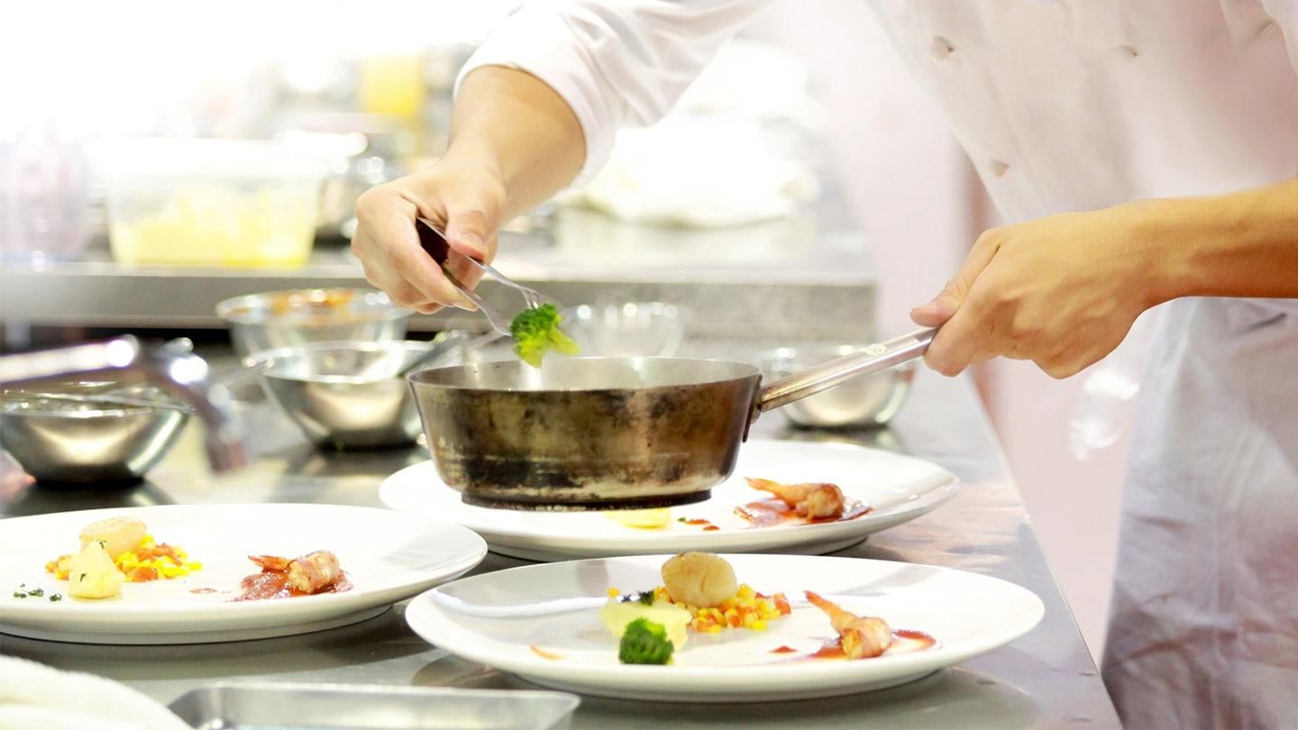 Chef sirviendo un plato gourmet en una cocina profesional, utilizando food solutions