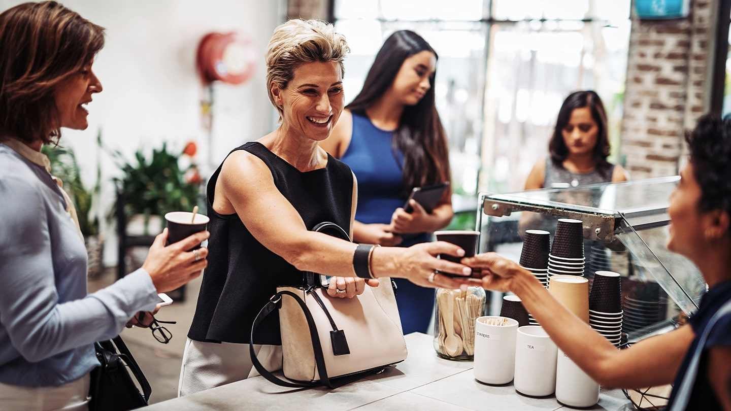 Personas reciben vasos desechables de café en un mostrador de una tienda de conveniencia