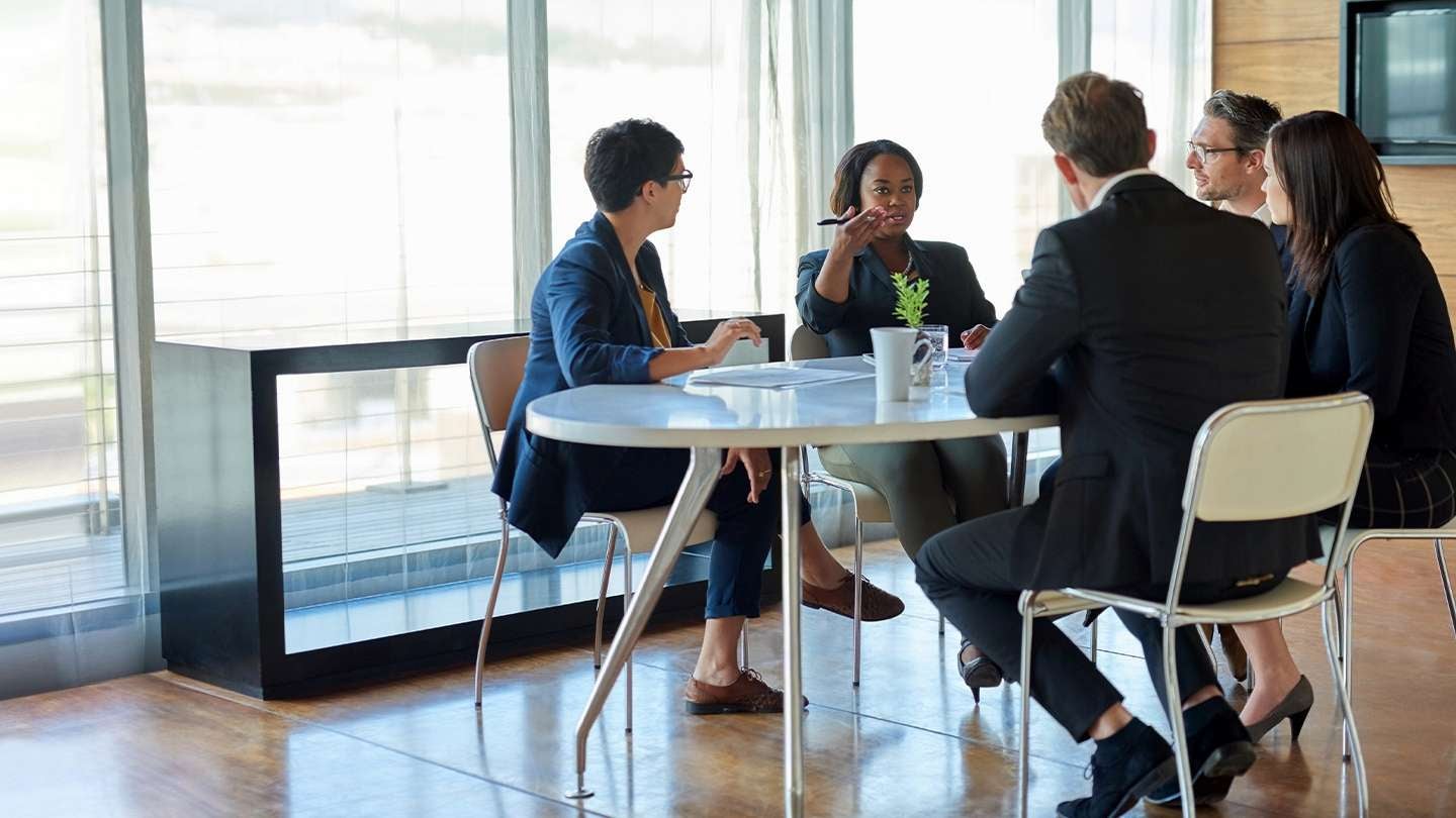Grupo en una mesa redonda discute documentos y planes de contingencia en una oficina bien iluminada.