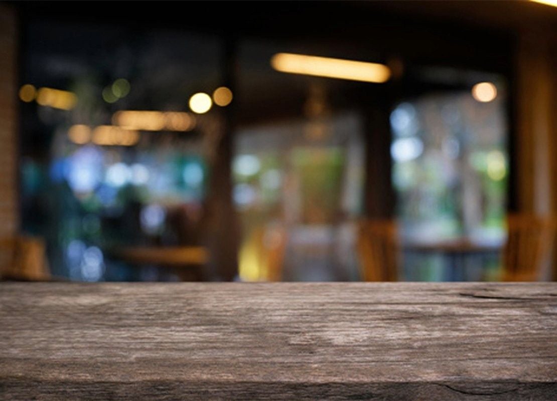 Superficie de mesa rústica con fondo desenfocado de iluminación para restaurante cálida