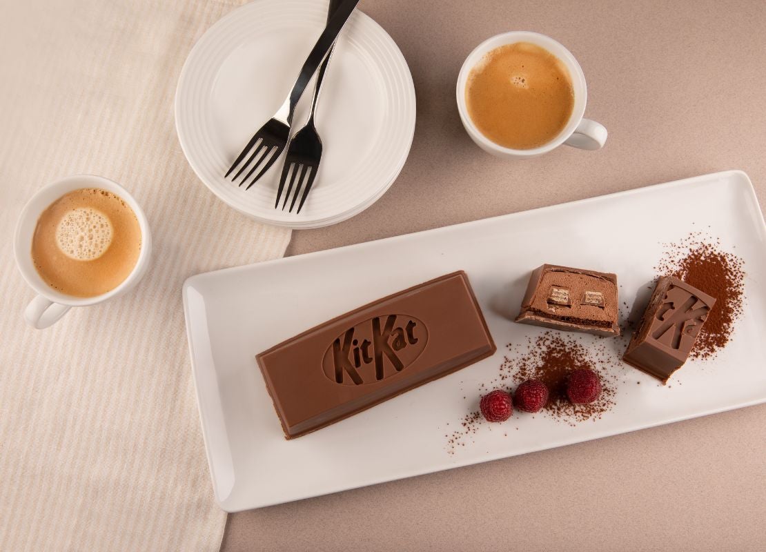 Postre de chocolate con forma de barra KITKAT® decorado con frambuesas y acompañado con café