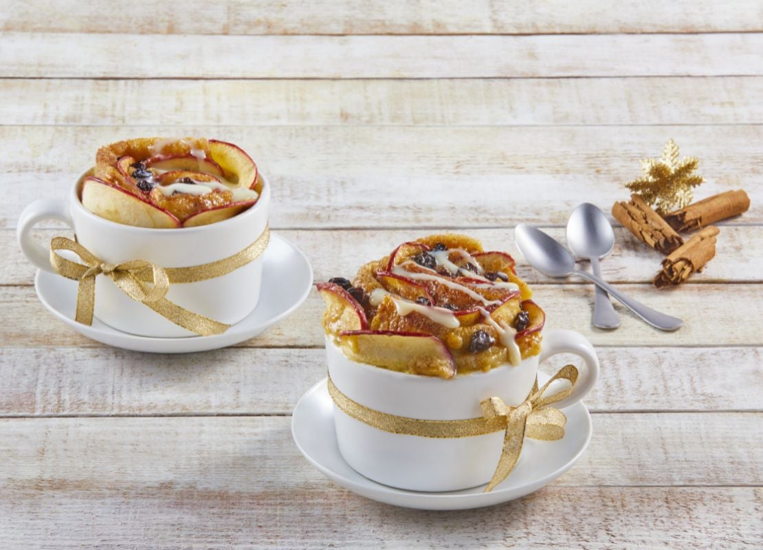 Postre de manzana y uvas servido en tazas de porcelana, decoradas con cintas doradas