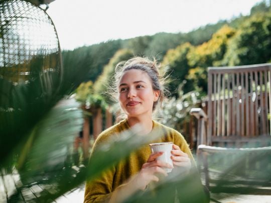 Persona disfrutando una degustación de café en un espacio al aire libre de un negocio gastronómico.