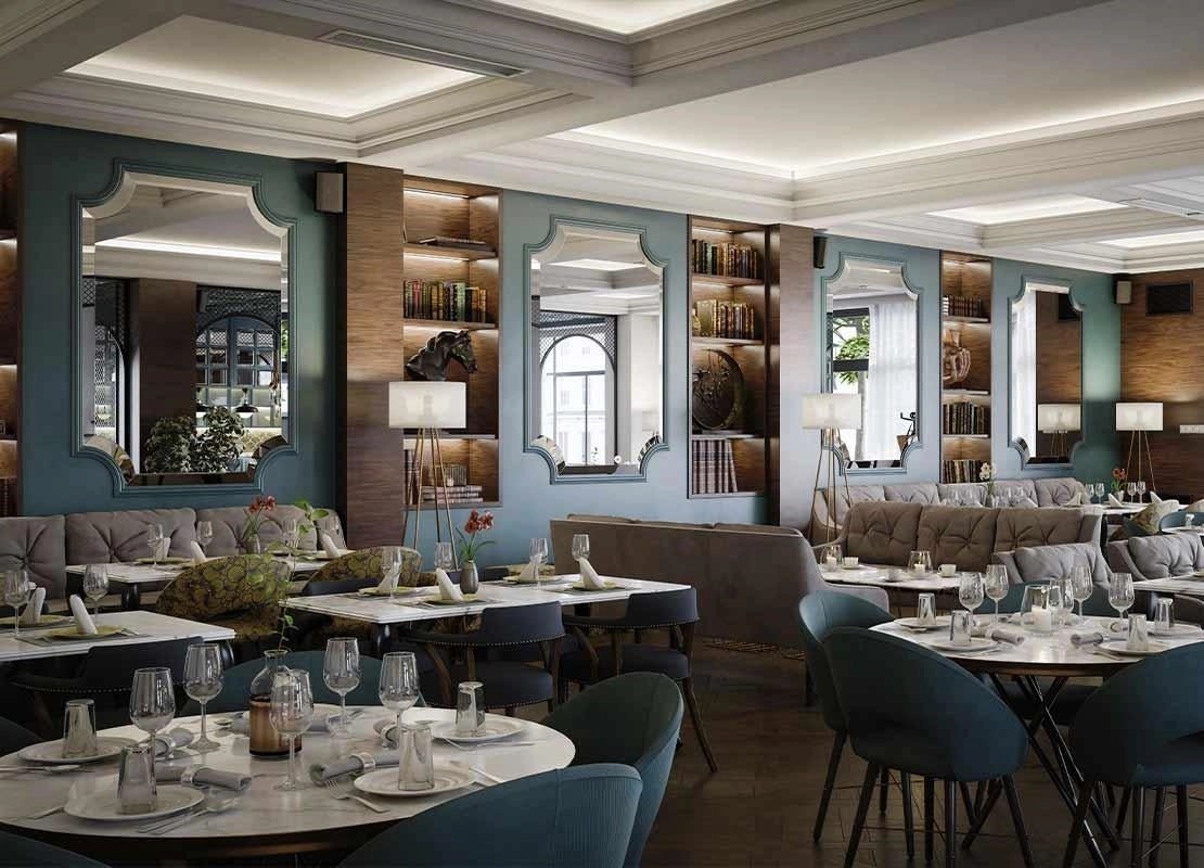 Vista interior de un restaurante con mesas y sillas vacías, decorado con espejos y paredes de color turquesa oscuro