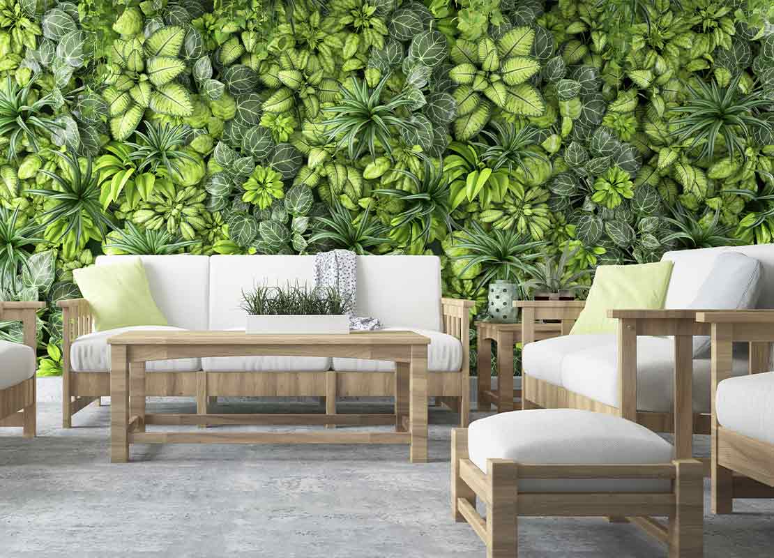 Terraza de restaurante con sofá, sillones, mesa de centro y una pared con plantas en macetas