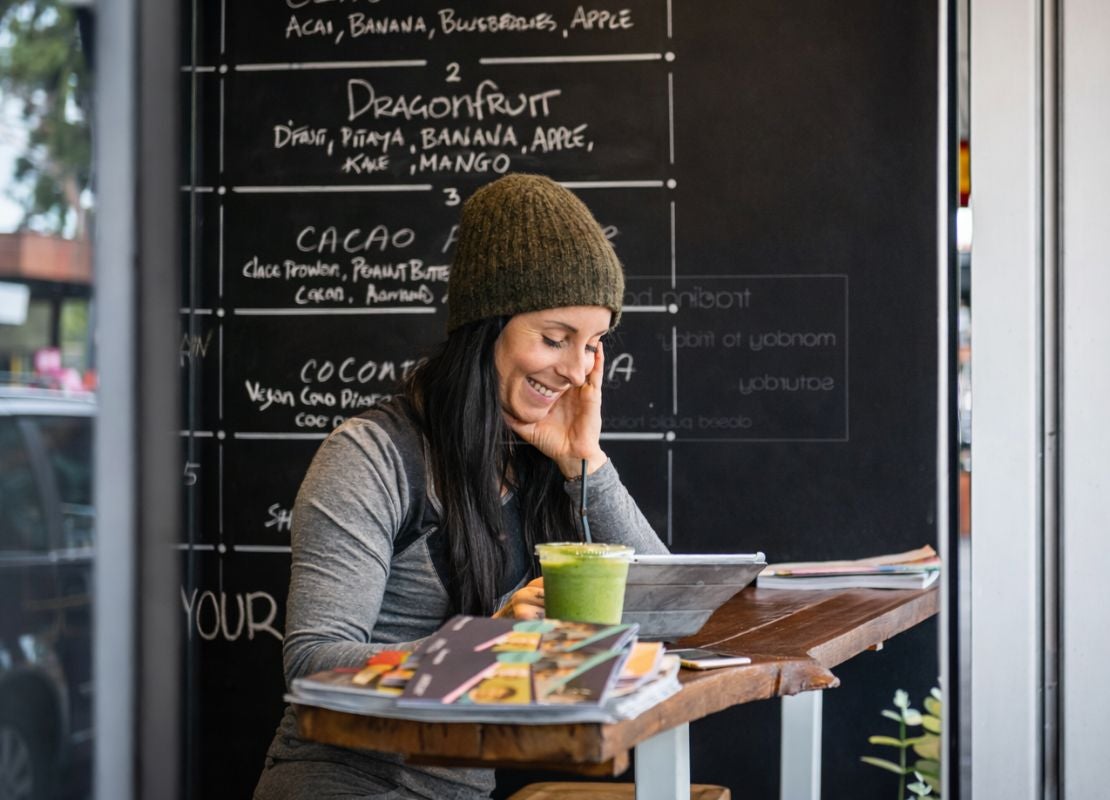 Mujer revisando emocionada el menú de temporada de un café.